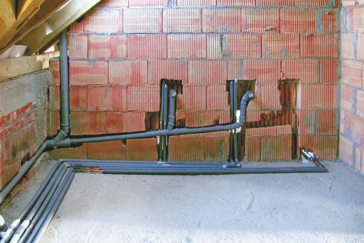 Instalacja hydrauliczna w trakcie budowy, widoczne rury i kształtki. To kluczowy etap, by wiedzieć, jak zrobić odpowietrzenie WC.